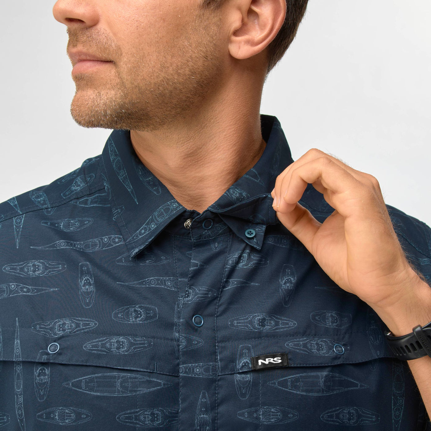 Close-up of man wearing navy NRS Men's Gear Shirt with kayak pattern and buttoned collar designed for water activities