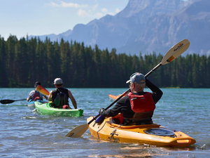 kayakers paddle on a serene lake in the rocky mountains